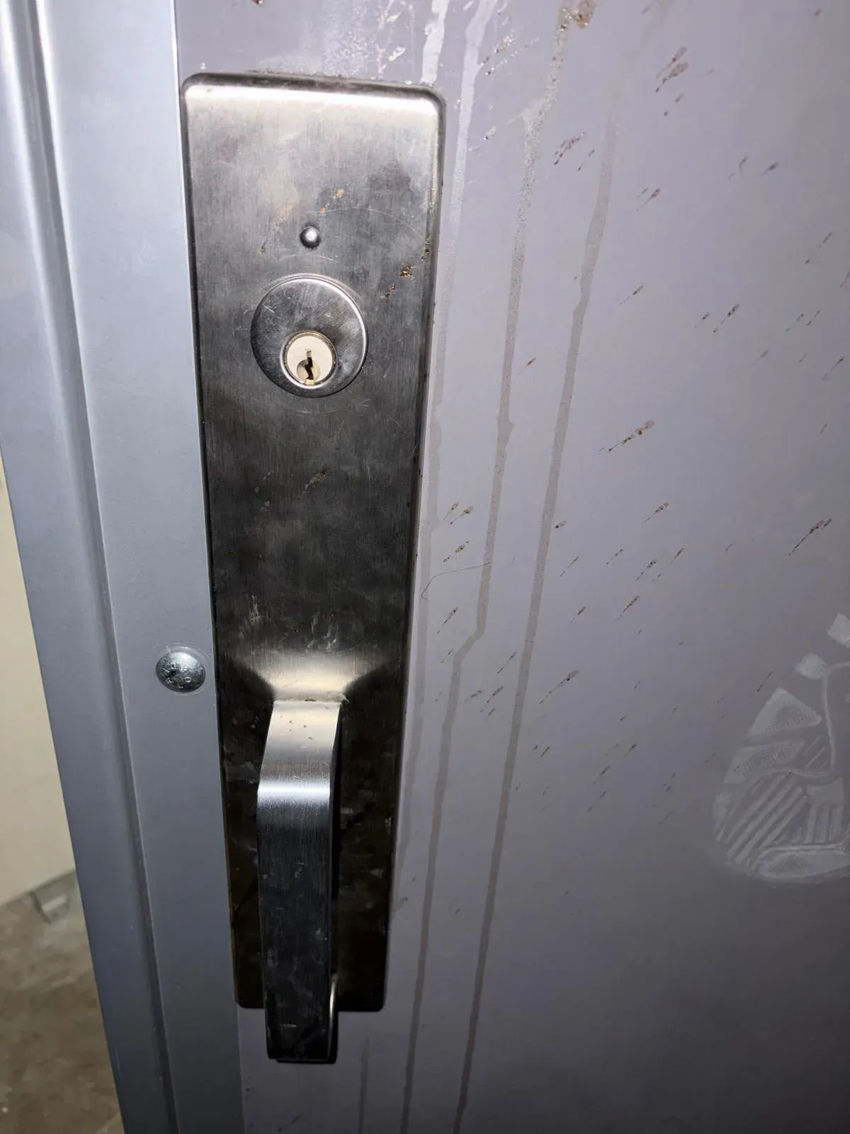 Black commercial lever handleset with a key cylinder on a metal door