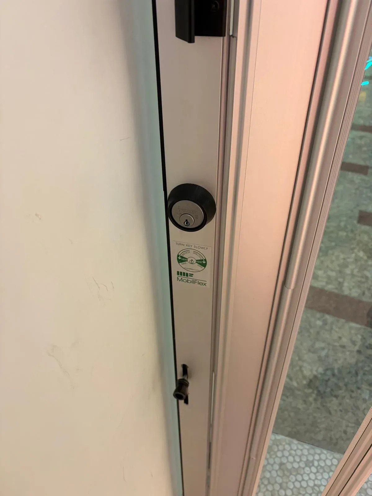 Rekeyed deadbolt cylinder on the edge of an aluminum door