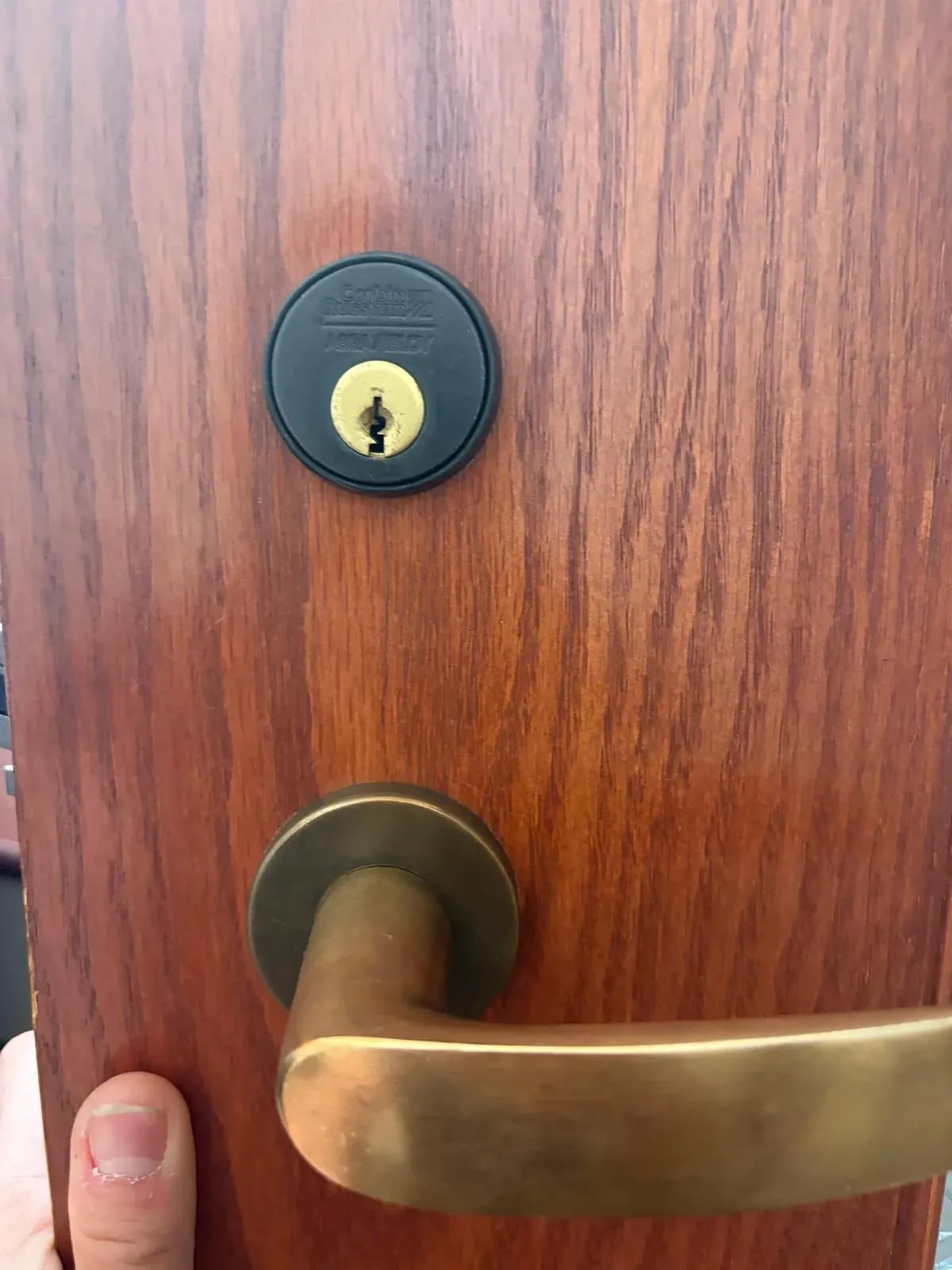 Deadbolt and brass lever handle on a wood door after a repair