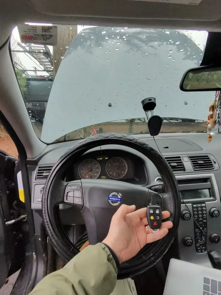 Hand holding a new Volvo remote key in front of the steering wheel